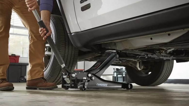 man lifting car in garage with Husky jack