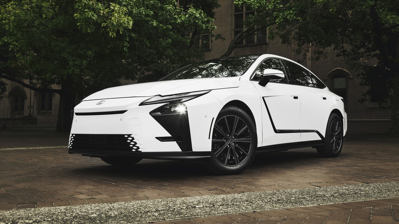 white 2027 Lexus ES 350h parked on a brick pathway under trees