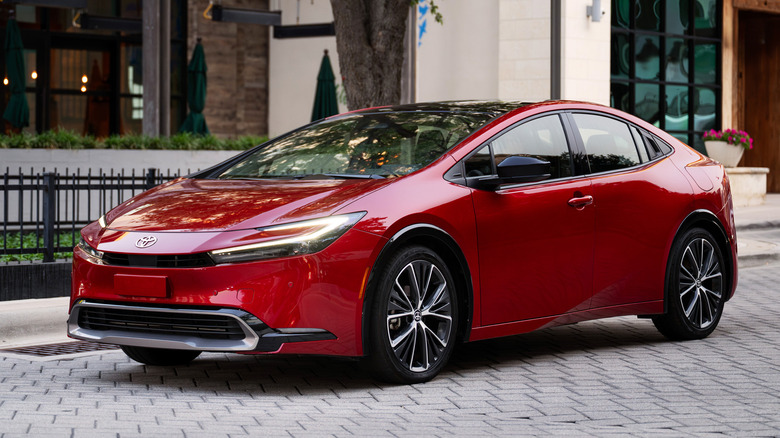 red 2027 Toyota Prius Supersonic driving on a stone tile urban street