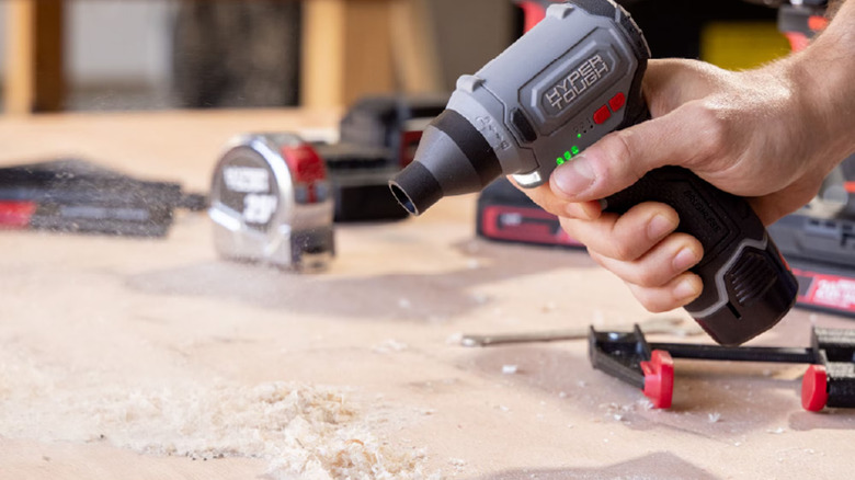 A person using blower on sawdust