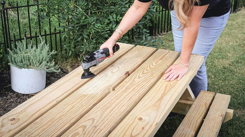 A woman using Oscillating Multi-Tool on table