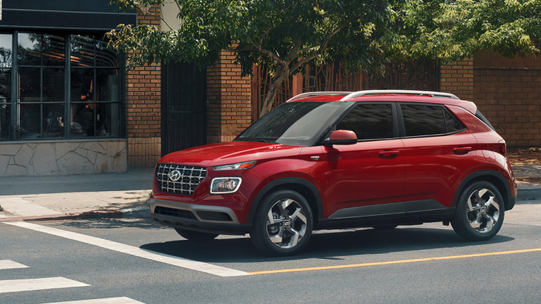 Side view of red 2026 Hyundai Venue parked on city street.
