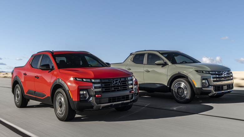 Front 3/4 view of green and orange Hyundai Santa Cruz driving in desert.