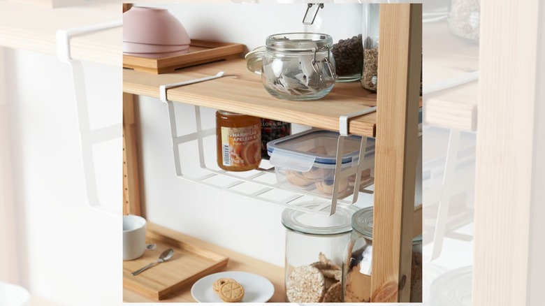 the PÅLYCKE clip-on basket containing jars of jam and a container of biscuits