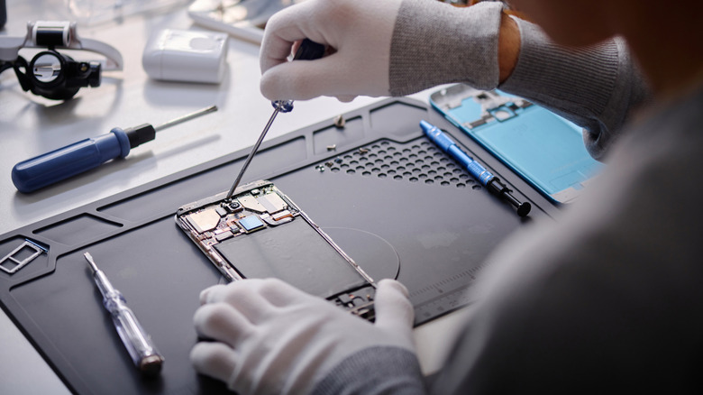 Professional with gloves and equipment repairing smartphone