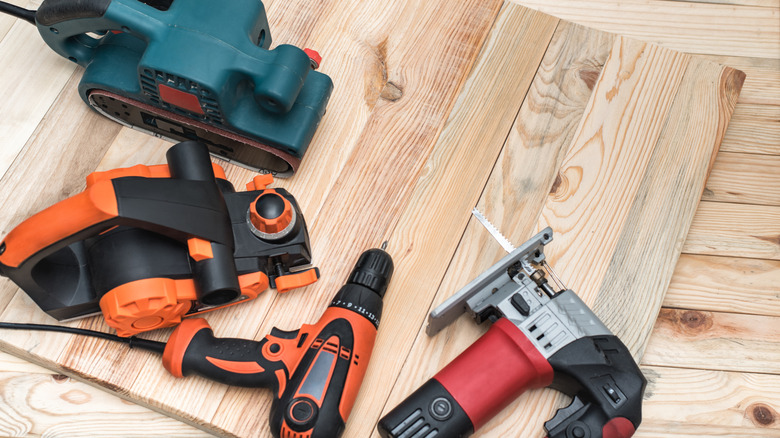 Four different colored tools on wooden boards.
