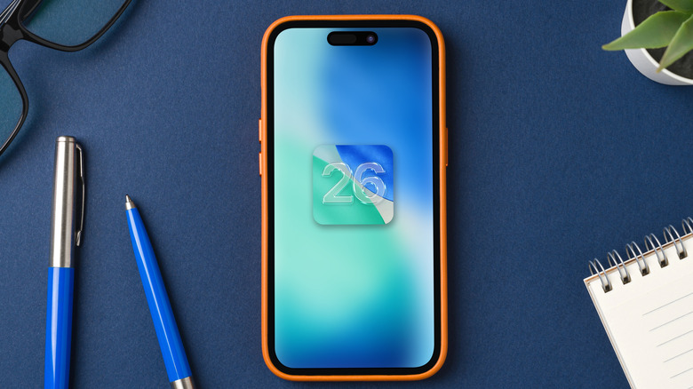 iPhone with iOS 26 logo on top of table with other items