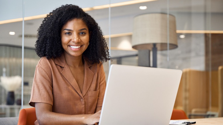 A woman at a laptop smiling at the camera