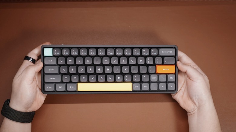 Close of up hands holding up a black keyboard