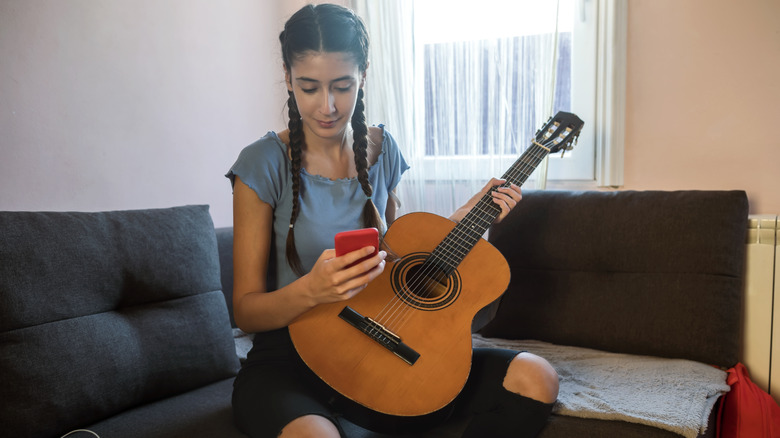 girl holding guitar and phone