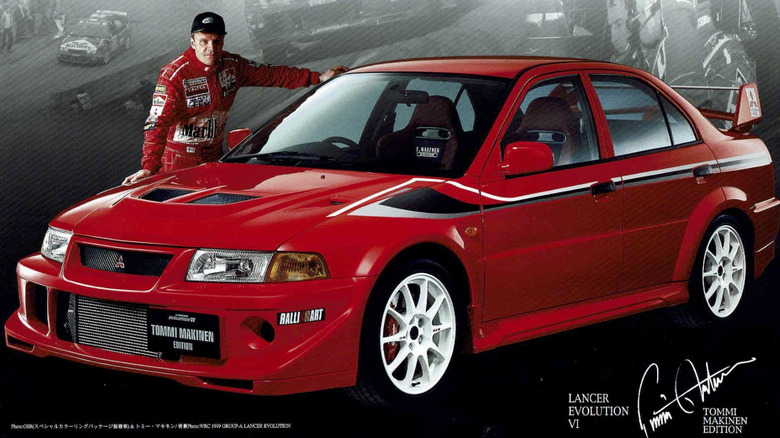 Rally driver Tommi Mäkinen standing beside the Mitsubishi Lancer Evolution VI TME.