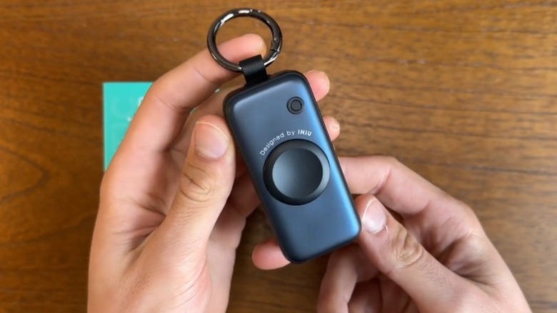 Hands holding the Iniu SnapGo Mini Portable Charger on top of a table