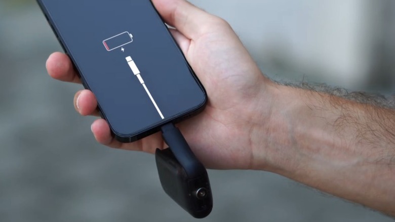 Hand holding a dead smartphone with a Rolling Square Tau 2 connected to the USB port