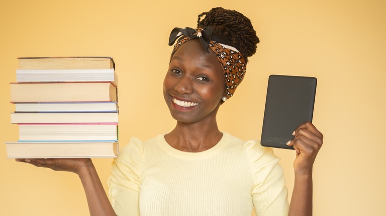 woman holding Kindle and books