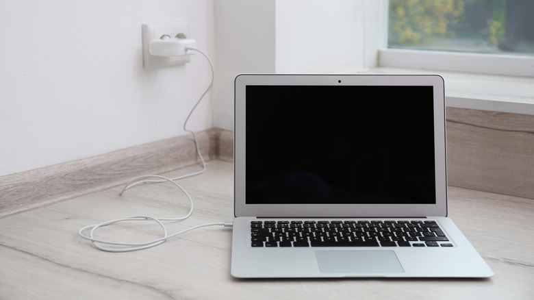 A modern laptop kept on the floor while charging