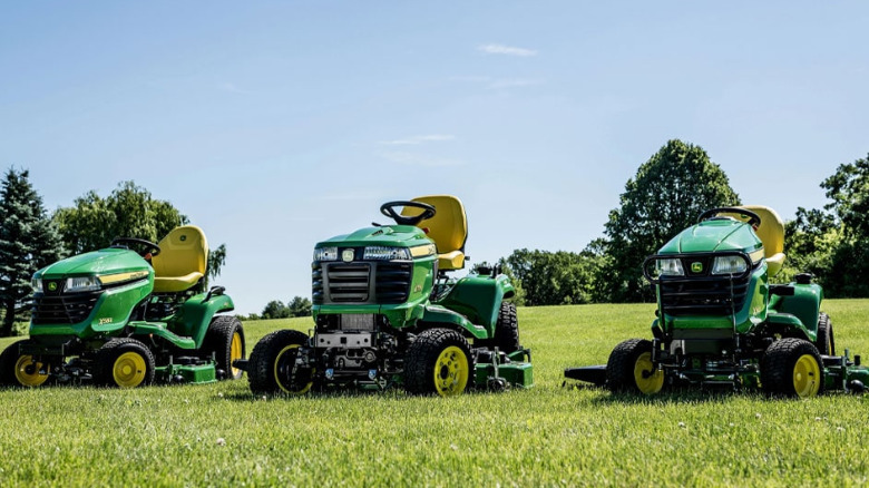Three John Deere Lawn Mower on a large green field.