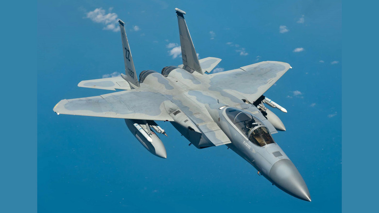 An F-15C flying on a mostly clear day against a blue sky