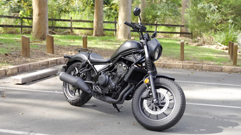 A black Honda Rebel 500 on a parking lot with the kickstand up, front 3/4 view