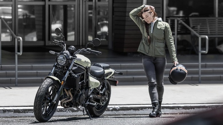 Rider holding helmet next to parked Kawasaki Eliminator