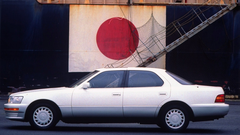 Toyota Lexus LS 400 on dock, w. Japanese flag draped fr. ship in rear.
