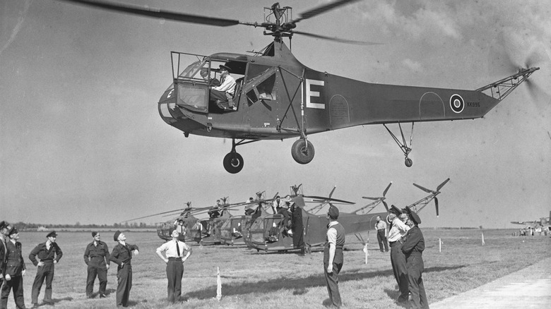 Sikorsky YR-4B hovering a few feet above interested military personnel
