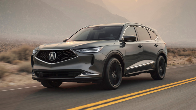 Acura MDX on a desert highway, front 3/4 view, dark gray exterior