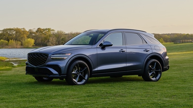 Bluish gray Genesis GV70 in a field, front 3/4 view, sunny day
