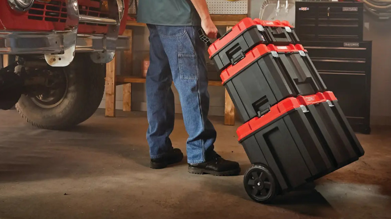 A person moving a tower of Versastack tool boxes in a garage.