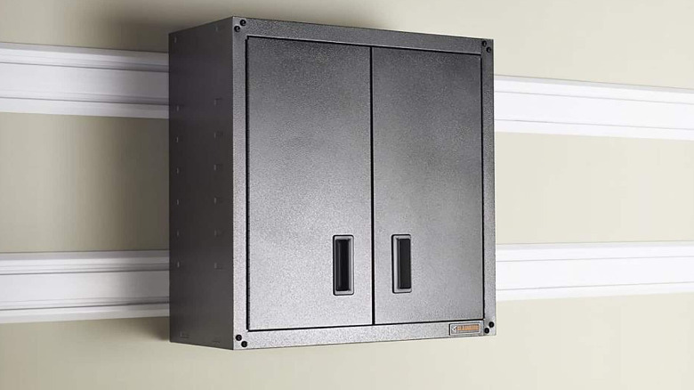 A black Gladiator full-door cabinet mounted on a wall with Gladiator GearTrack channels.