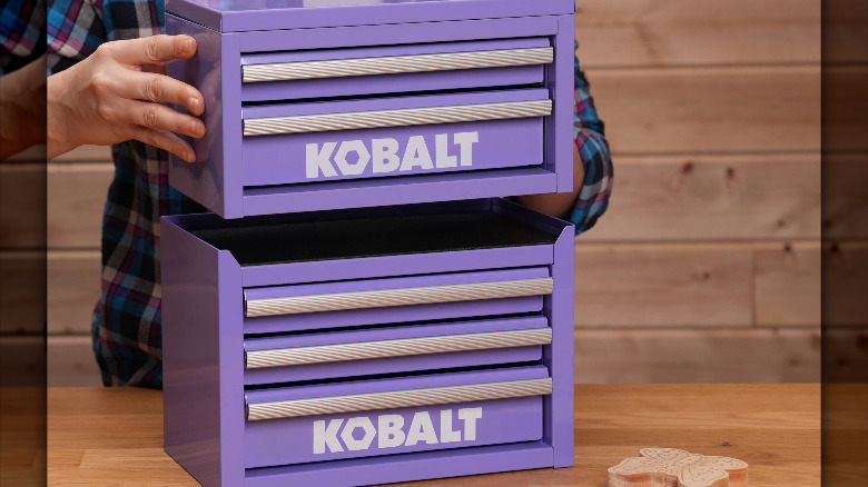 A person stacking two purple Kobalt mini toolboxes.