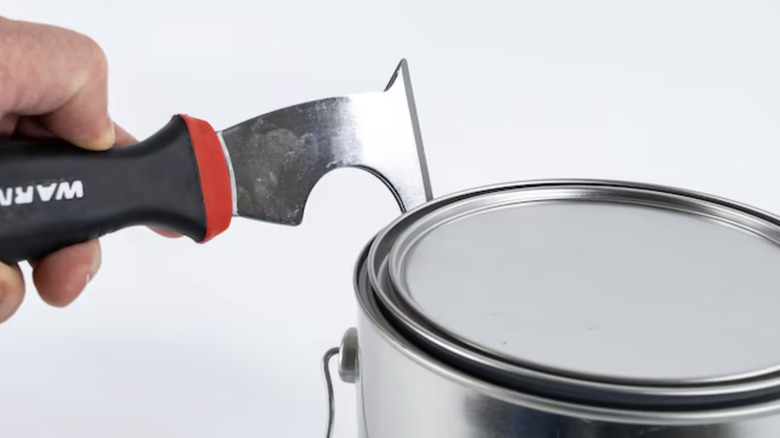 person opening paint can with multi-tool
