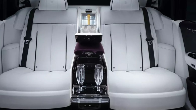 Backseat of a car with two champagne flutes and a cooler in the middle