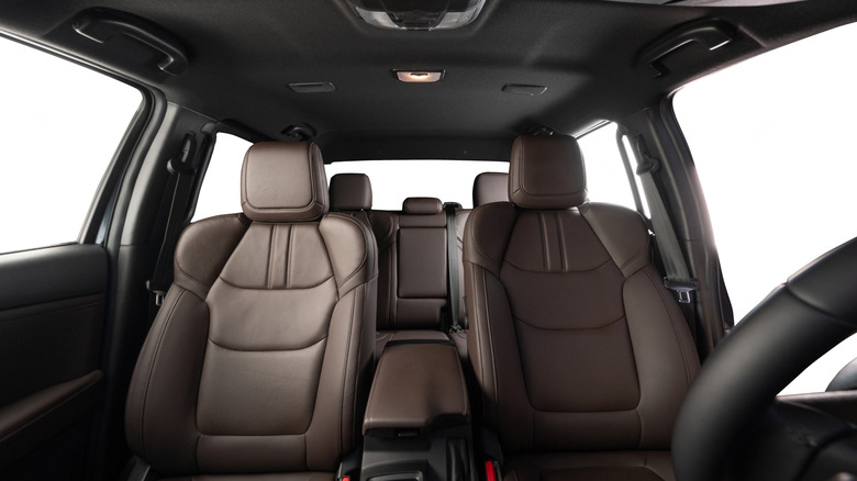 An interior view of a car looking backward with brown seats and black upholstery.