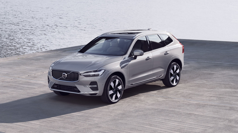 A Volvo XC60 in silver next to a coastline, front 3/4 view
