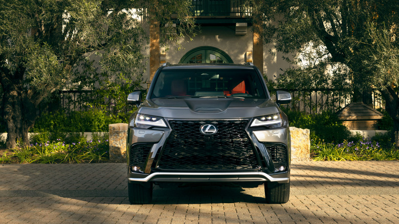 2026 Lexus LX700h hybrid in front of classical home with greenery, front-facing view