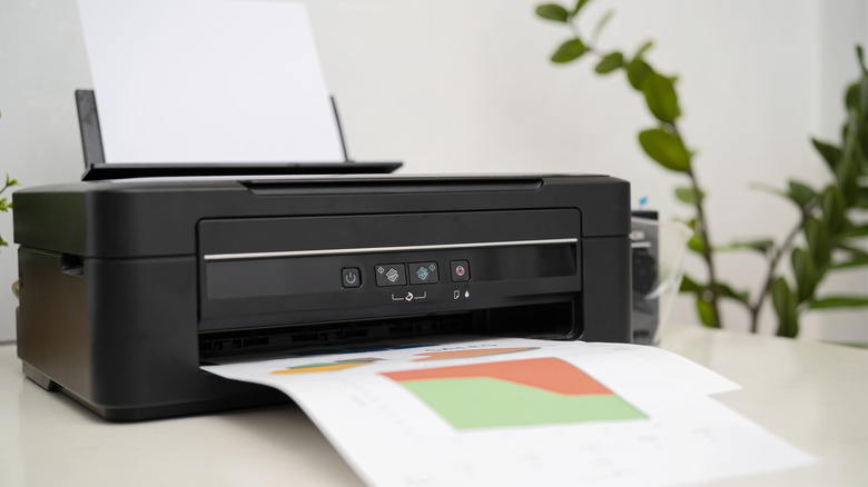 Close-up of a printer with printed sheets in its tray.