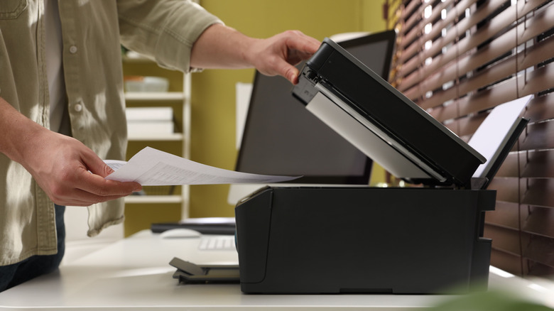 Person placing paper in a printer.