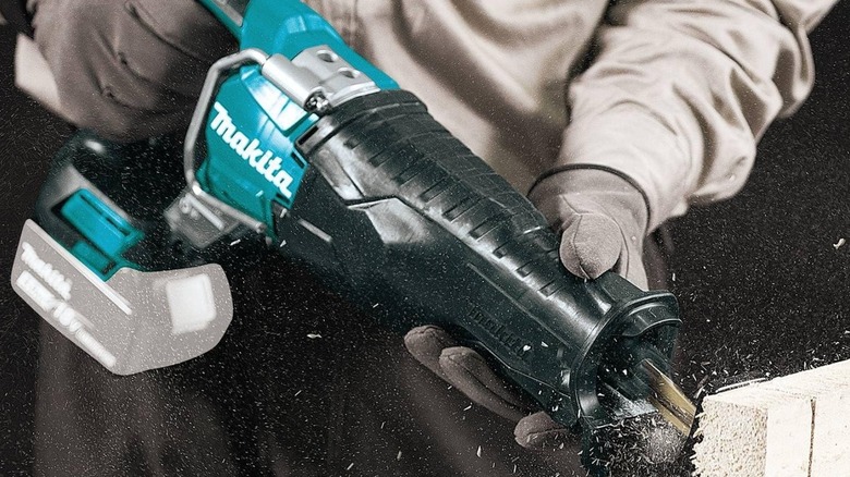 Person cutting fiber board with Makita XRJ05Z 18V Cordless Brushless Reciprocating Saw