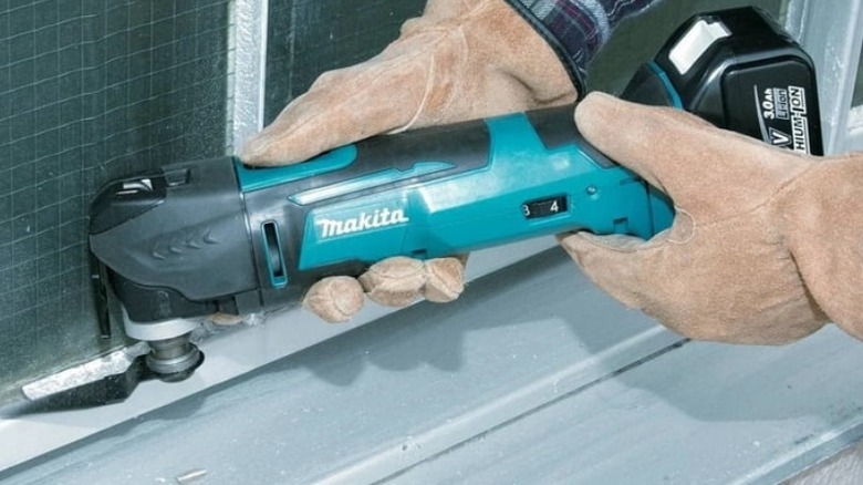 Person cutting cement backerboard with Makita XMT03Z 18V LXT Cordless Oscillating Multi-Tool