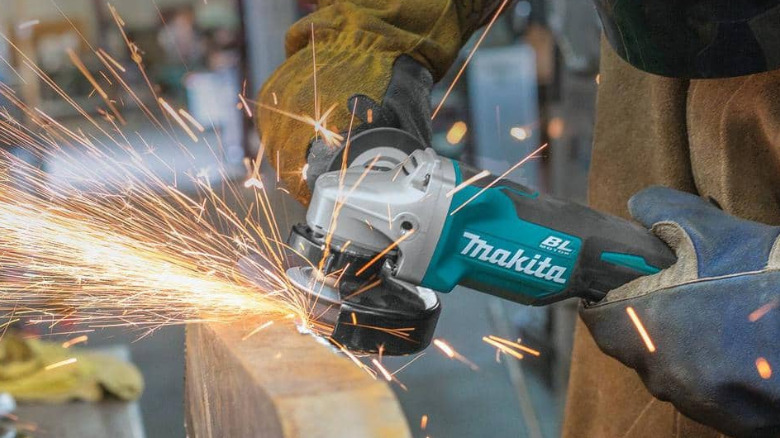 A person wearing protective gear uses a Makita angle grinder.