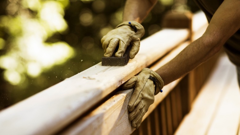 Person sanding banister on a deck