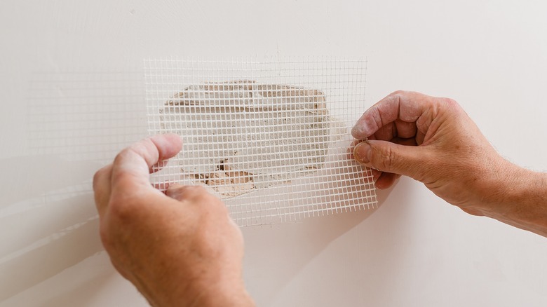 Person applying drywall patch