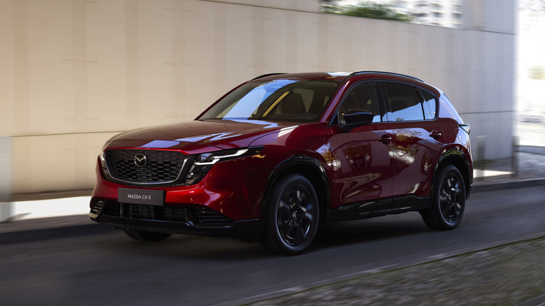 A red Mazda CX-5 SUV driven through an urban setting.