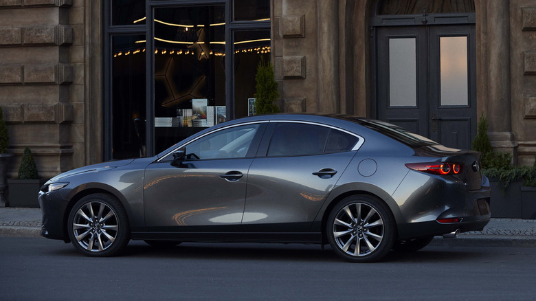A gray Mazda3 sedan parked in front of a grand Victorian building.