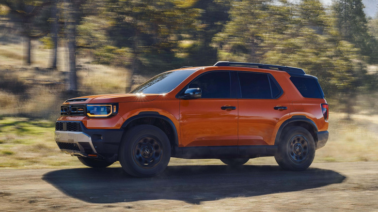 Side view of orange Honda Passport on mountain trail.