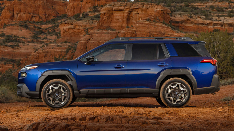 Side view of blue Subaru Outback parked on desert trail.