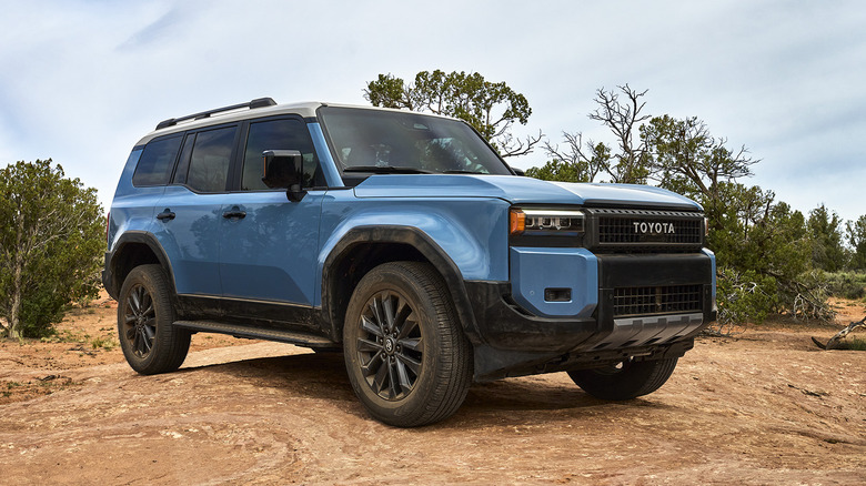 Front 3/4 view of blue Toyota Land Cruiser on desert trail.