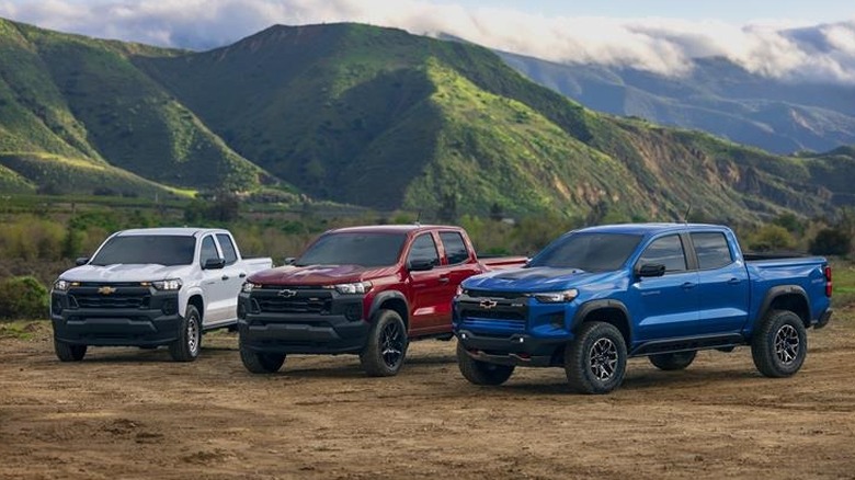 Three 2026 Chevrolet Colorado pickup trucks parked in mountains.