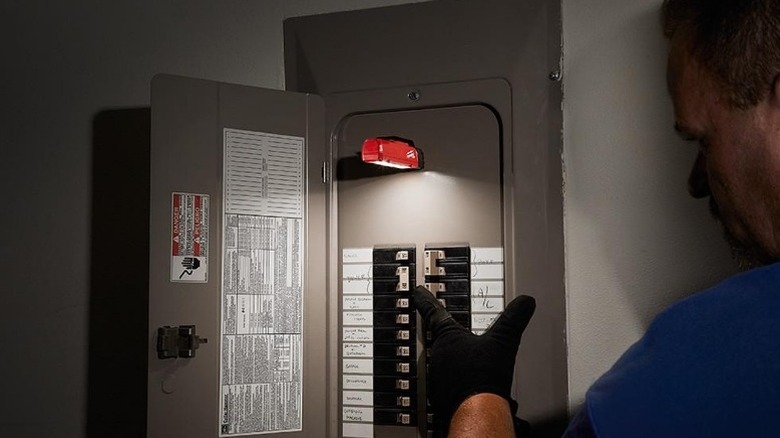 Person using Milwaukee Rover Magnetic Flood Light on fuse box