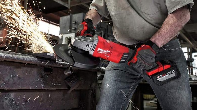 A person using a Milwaukee angle grinder on metal.